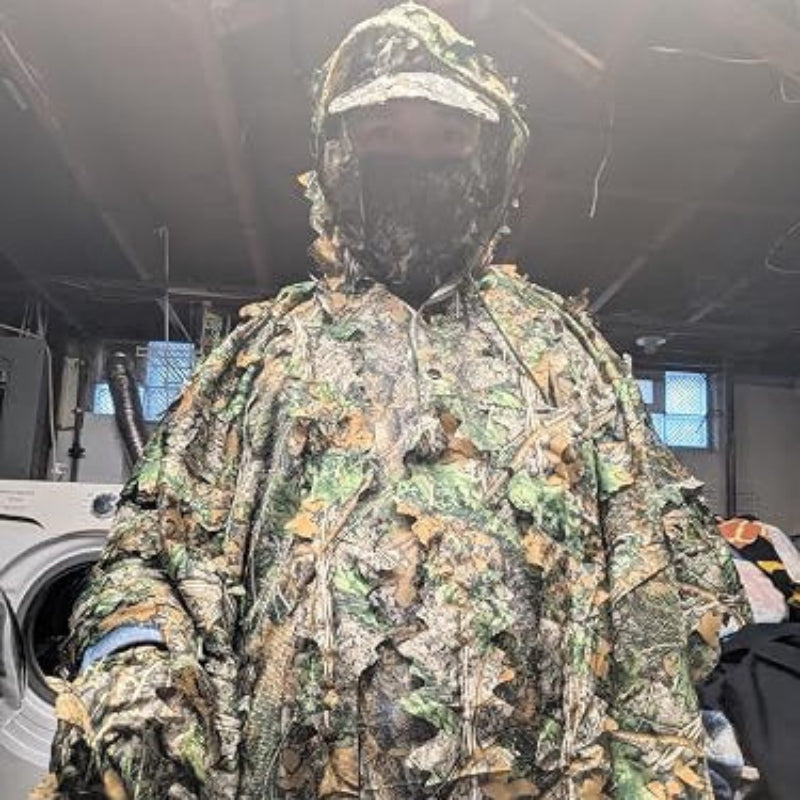 Indoor fit testing of the GhillieLabs unisex adult adjustable camouflage cape, showcasing the integrated hood and all-climate open-weave ventilation layer.