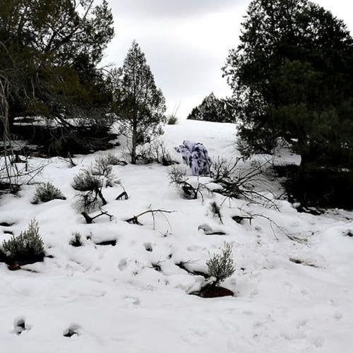 A wide-angle field integration test showcasing the flawless profile disruption of the winter snow camouflage ghillie suit on a snow-covered hillside.