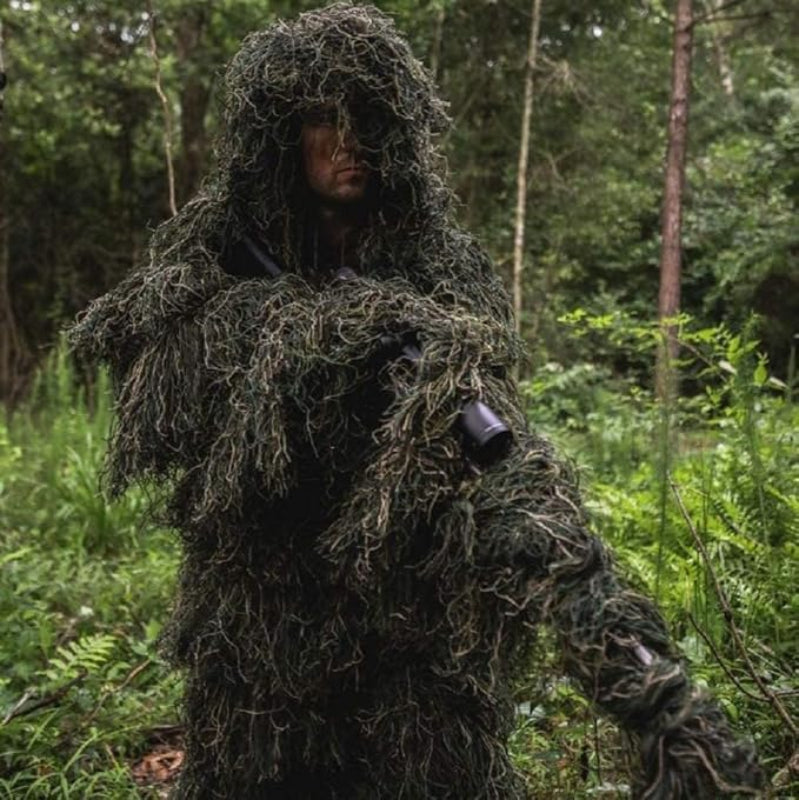 An observer wearing the heavy-duty woodland ghost ghillie suit while holding professional telephoto equipment, shattering the human silhouette in thick forests.