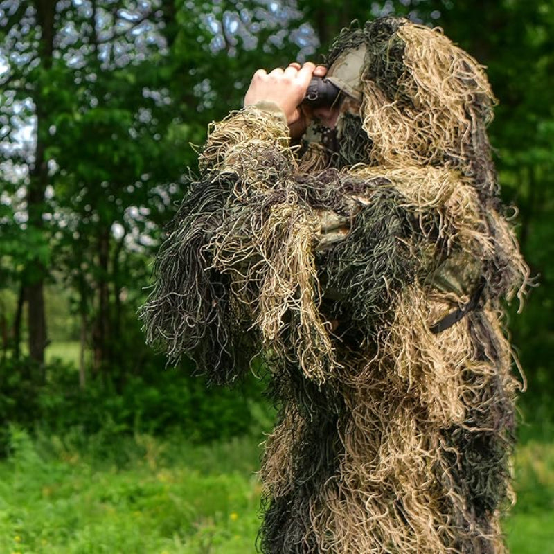 Side view of an observer in Field Grassland camouflage utilizing binoculars for non-invasive bird watching in transitioning dry fall vegetation.