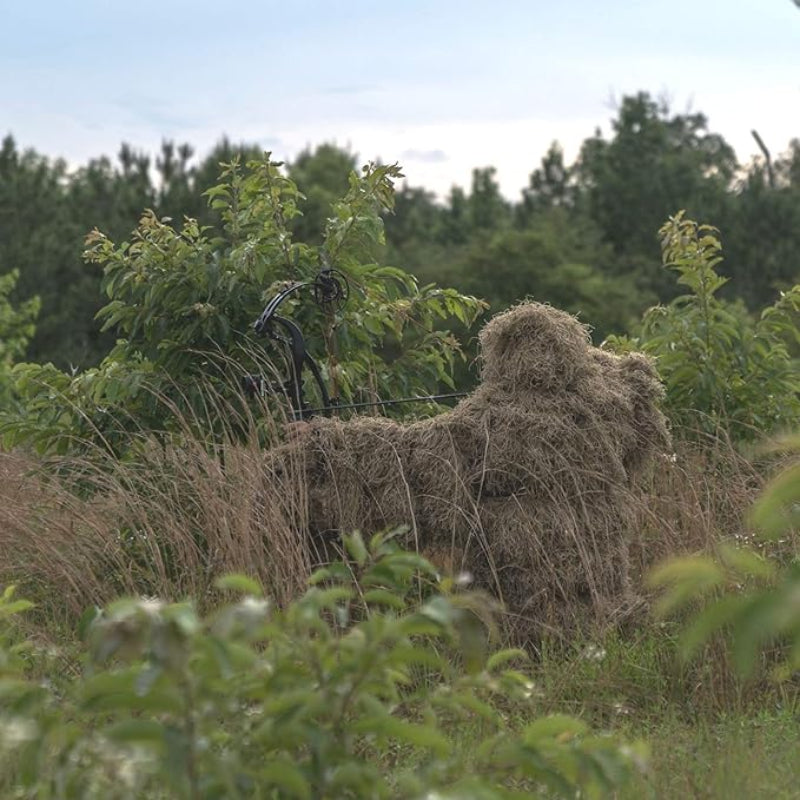 An adult nature observer positioned in dense brush, showcasing the interlocking double-stitch durability that prevents fiber shedding on frozen or dry branches.