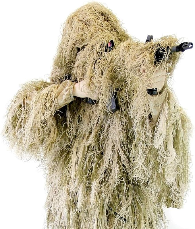 An observer in Field Grassland coyote tan ghillie suit holding a camera setup wrapped with matching gear and lens camouflage wrap.