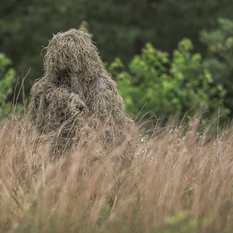 A professional wildlife photographer standing motionless in tall, dry grass to blend into a transitioning savanna or desert fringe micro-environment.
