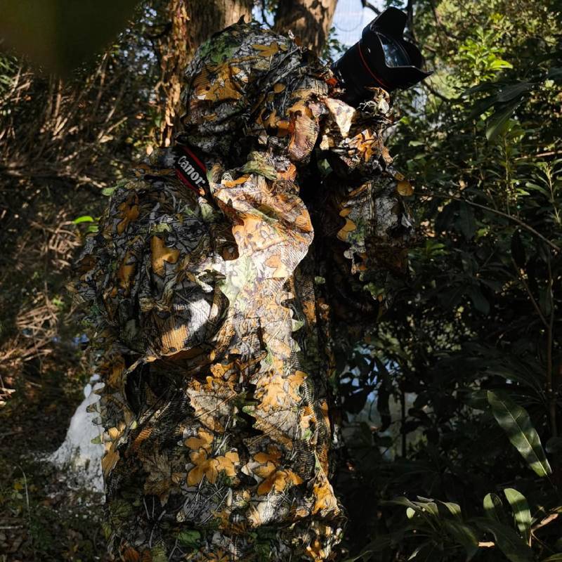 A wildlife photographer moving through heavily wooded areas and thick tall brush without catching branches, utilizing premium laser-cut leaves.