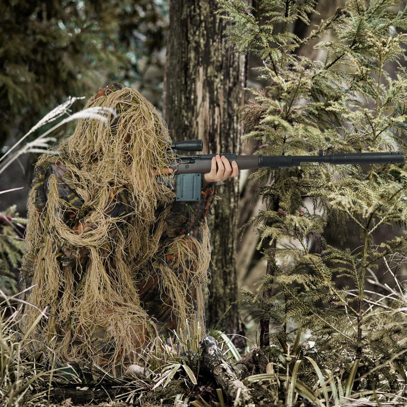 Complete spatial integration of a tracker kneeling in dry woodland brush wearing the brown-toned dual-disruption ghillie system.