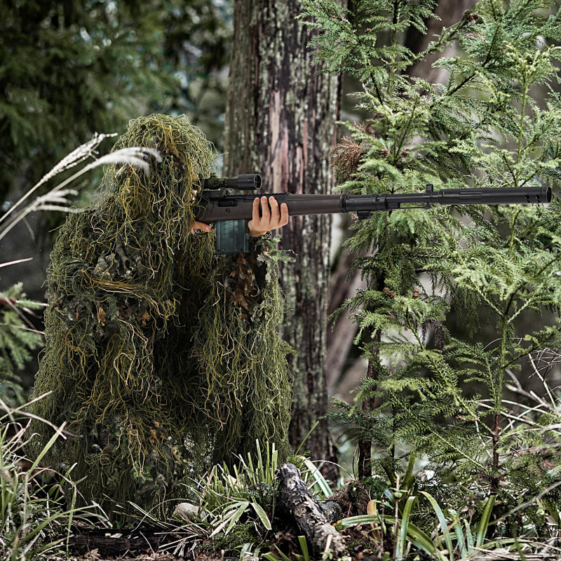 Side profile of an observer blending seamlessly into dark forest vegetation using the dual-texture woodland ghillie kit